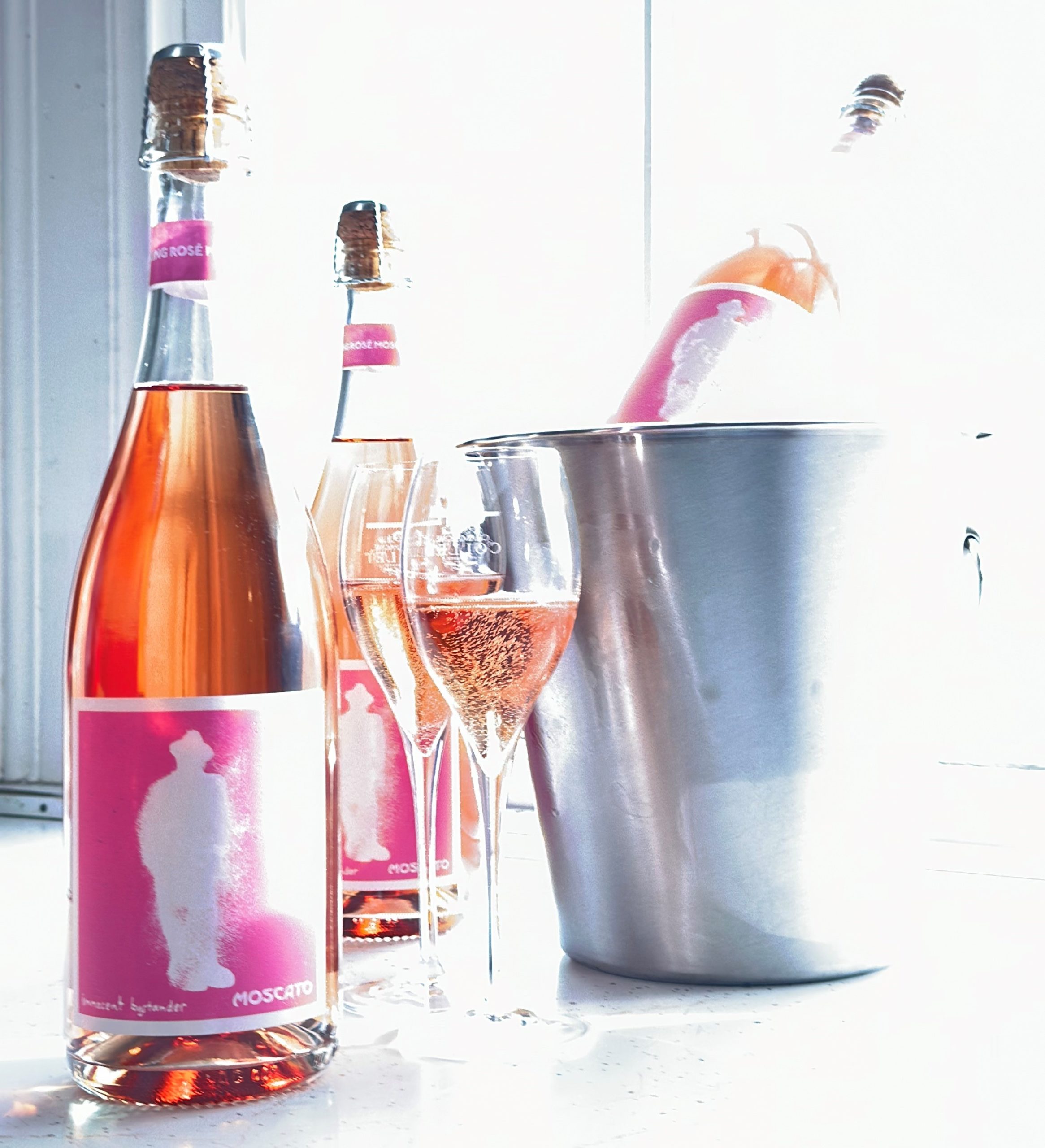 bottles of pink sparkling wine and an ice bucket with wine glasses
