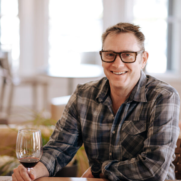man with glasses sits with wine glass