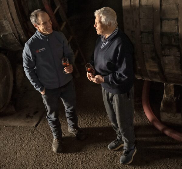 two men talk in a winery